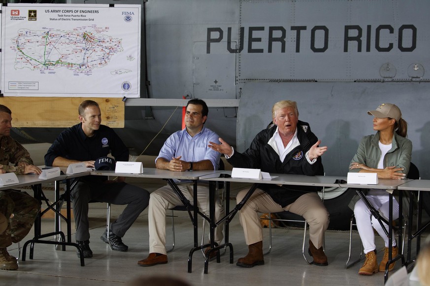 President Donald Trump and first lady Melania Trump participate in a briefing on hurricane recovery efforts with first responders at Luis Muniz Air National Guard Base, Tuesday, Oct. 3, 2017, in San J ...