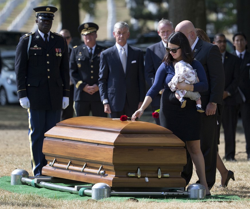 Meghan Florich, widow of Army Staff Sgt. Thomas Florich III, holds their baby as she places a rose on his casket during a burial service at Arlington National Cemetery in Arlington, Va., Tuesday, Sept ...