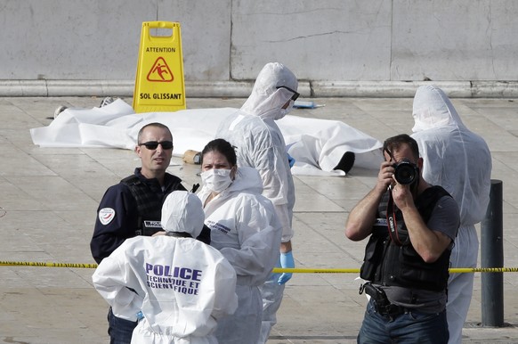 Investigative police officer work by a body under a white sheet outside Marseille &#039;s main train station Sunday, Oct. 1, 2017 in Marseille, southern France. A man with a knife attacked people at t ...