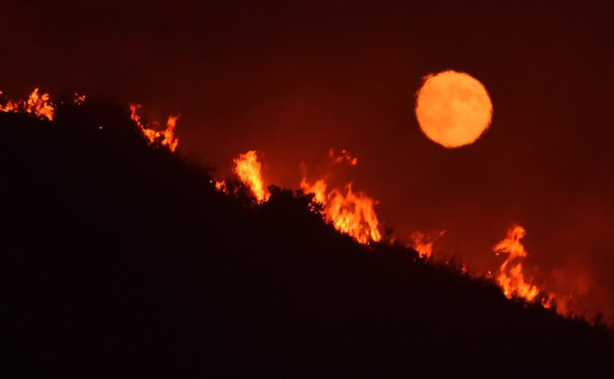 This Saturday, July 8, 2017, photo released by the Santa Barbara County Fire Department shows the moon rising over flames on a hilltop near Highway 166 east of Santa Maria, Calif., in what is known as ...