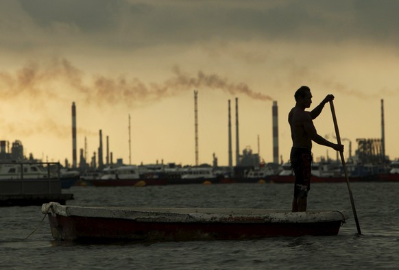 Ein Fischer vor einer Öl-Raffinerie in Singapur.