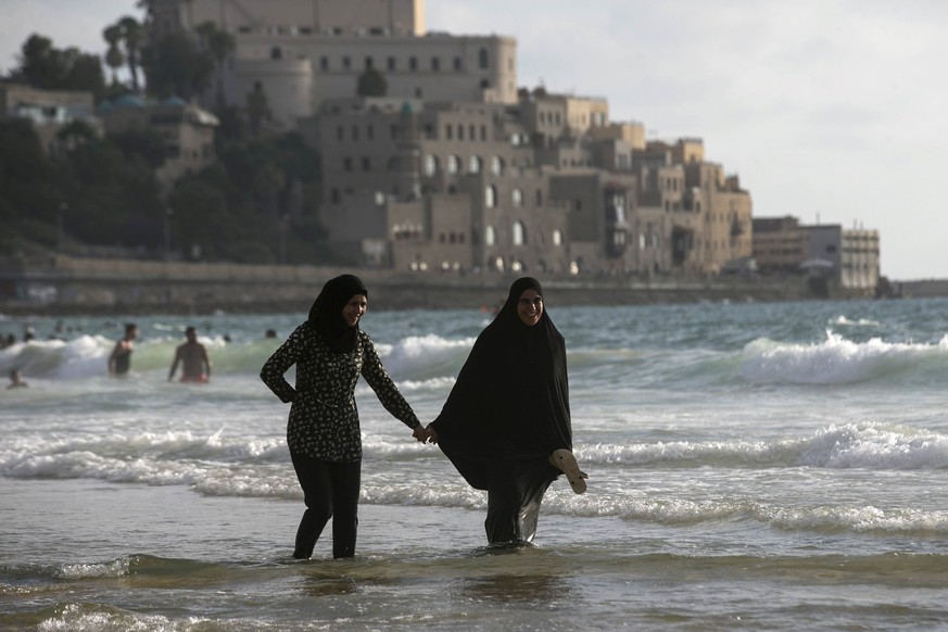 Muslim women walk along beach of the Mediterranean in Tel Aviv during Eid al-Fitr, which marks the end of the holy month of Ramadan July 19, 2015. Thousands of Palestinians used permits given by the I ...