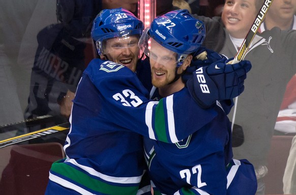 Vancouver Canucks&#039; Daniel Sedin, right, celebrates with his twin brother Henrik Sedin, both of Sweden, after scoring the winning goal against the Montreal Canadiens during overtime of an NHL hock ...