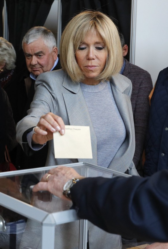 epa05922887 Brigitte Trogneux (C), wife of Emmanuel Macron, head of the political movement En Marche! (Onwards!) and candidate for the 2017 French presidential election, casts her ballot in the first  ...