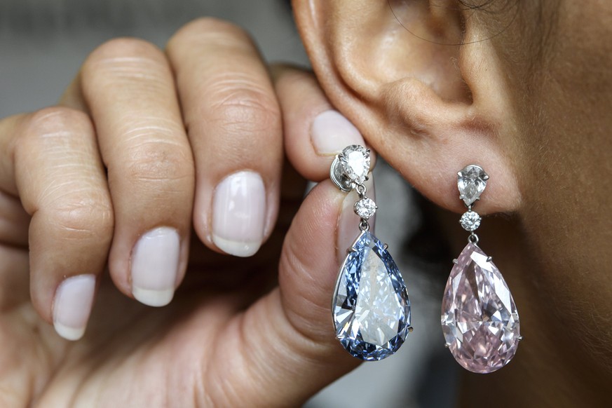 epa05957257 A Sotheby&#039;s employee displays the Apollo blue diamond and the Artemis pink diamond earrings during a preview at the Sotheby&#039;s, in Geneva, Switzerland, 11 May 2017. The earrings,  ...