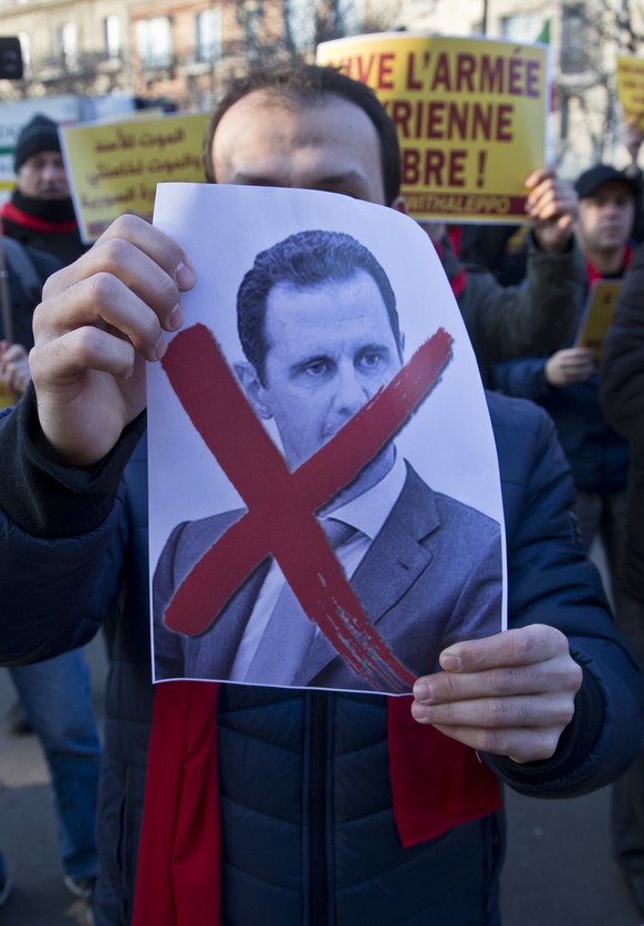 A Syrian migrant holds a picture of Syrian President Bashar Assad during a gathering to protest against the war in Aleppo outside the Iranian embassy in Paris, Saturday, Dec. 17, 2016. The protest was ...