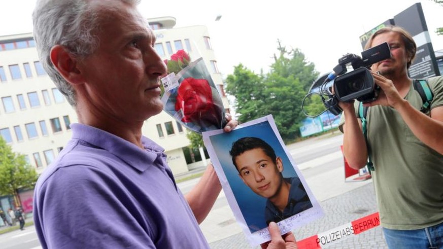 Naim Zabergja steht mit einem Foto seines getˆteten Sohnes Dijamant am 23.07.2016 vor Medienvertretern am Olympia-Einkaufszentrum in M¸nchen (Bayern), das die Polizei nach einer Schieﬂerei mit Toten u ...