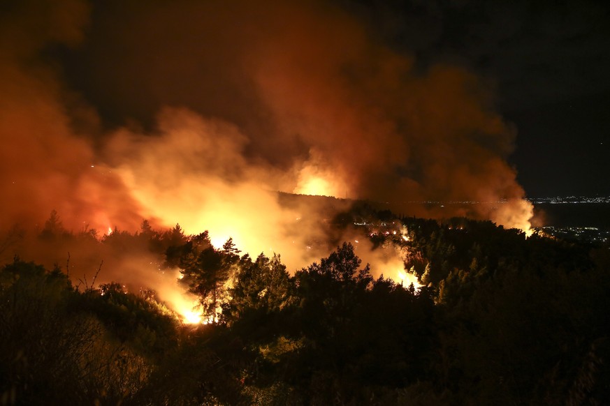 Flames and smoke rise from a forest fire at Kalamos village, north of Athens, on Sunday, Aug. 13, 2017. Fires breaking out across Greece have stretched firefighting capabilities to the limit, authorit ...