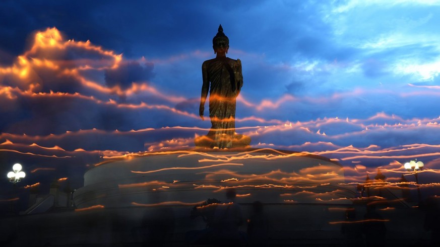 epa05319486 Thai Buddhists hold candles as they circle in prayer a statue at the Buddha Monthon park to celebrate Buddha Day in Nakon Pathom Province, west of Bangkok, Thailand, 20 May 2016. Thai Budd ...