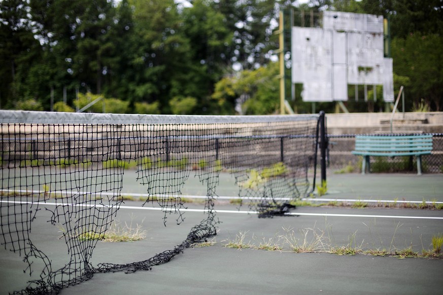 In this Tuesday, July 19, 2016 photo, the derelict netting and scoreboard in the background on a tennis court stand at the Stone Mountain Tennis Center, home of the 1996 Summer Olympic Games tennis ev ...