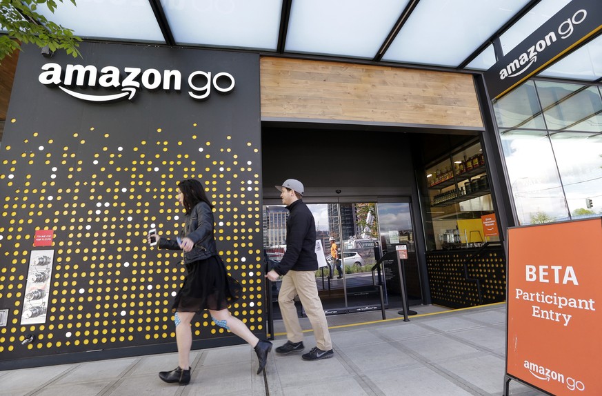 FILE - In this Thursday, April 27, 2017, file photo, people walk past an Amazon Go store, currently open only to Amazon employees, in Seattle. Amazon Go shops are convenience stores that don&#039;t us ...