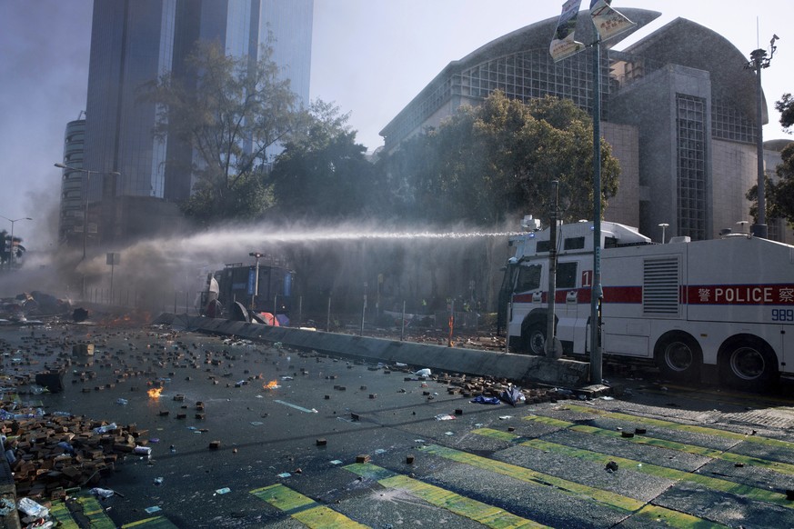An armored police vehicle sprays a water cannon during a confrontation with protestors at Hong Kong Polytechnic University in Hong Kong, Sunday, Nov. 17, 2019. A Hong Kong police officer was hit in th ...