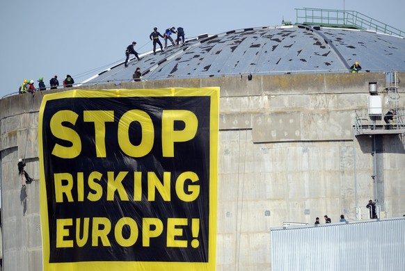 epaselect epa04130680 A protest banner from Greenpeace with text reading &#039;Stop Risking Europe!&#039; is unfurled by activists at the Fessenheim nuclear power plant in Fessenheim, France, 18 March ...