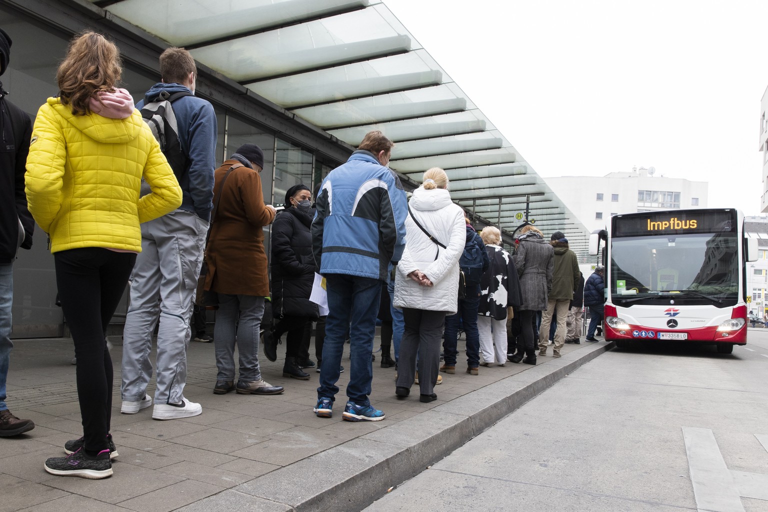 People wait in a long queue to get vaccinated against the COVID-19 virus in a public bus, that drives around the city and offers the COVID-19 vaccination without appointments and for free in Vienna, A ...