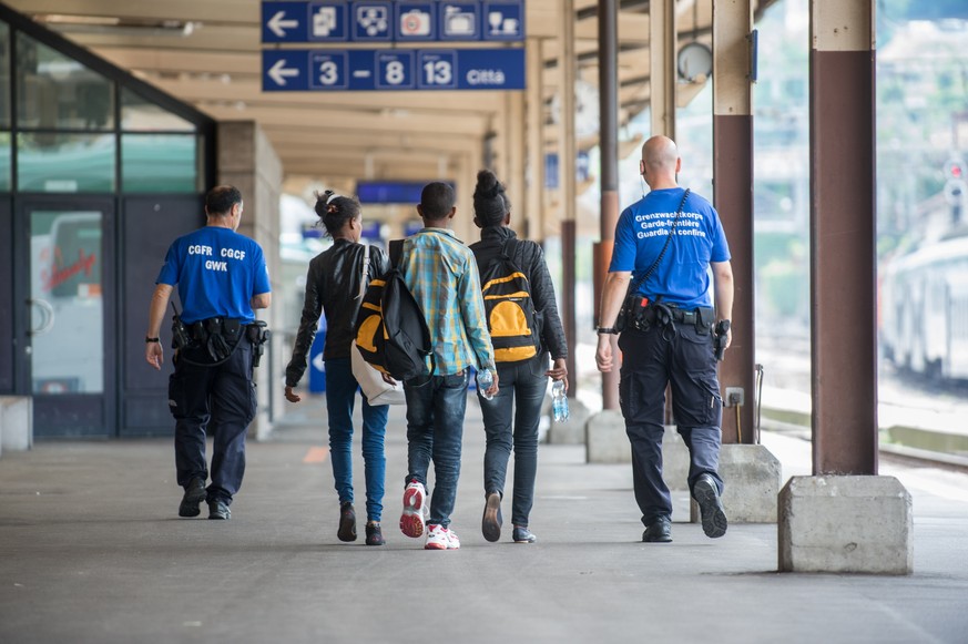 Ein Grenzwaechter begleitet Fluechtlinge, am Dienstag, 12. Juli 2016, auf dem Bahnhof in Chiasso. Die Fluechtlinge wollten mit einem Bus nach Deutschland gelangen, konnten aber an der Schweizer Grenze ...