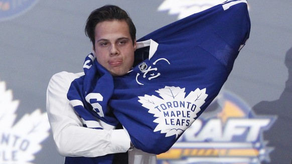 Jun 24, 2016; Buffalo, NY, USA; Auston Matthews puts on a team jersey after being selected as the number one overall draft pick by the Toronto Maple Leafs in the first round of the 2016 NHL Draft at t ...