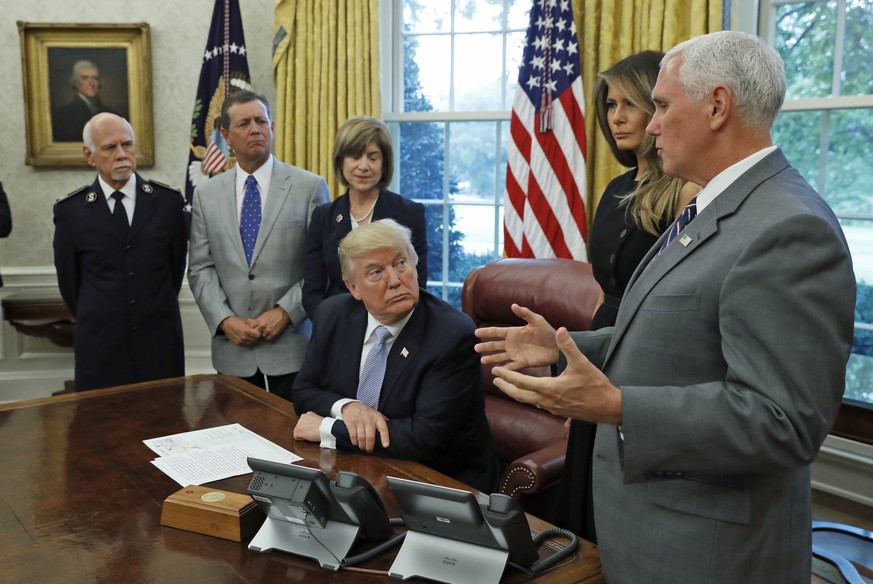 President Donald Trump looks at Vice President Mike Pence as he speaks about Harvey in the Oval Office of the White House with Commissioner David Hudson, National Commander, Salvation Army USA, left,  ...