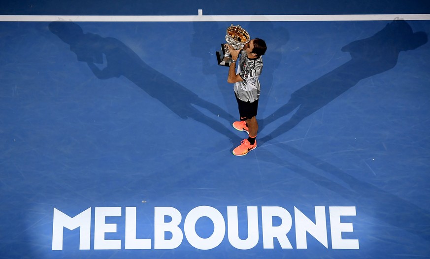 Switzerland&#039;s Roger Federer holds his trophy after defeating Spain&#039;s Rafael Nadal during the men&#039;s singles final at the Australian Open tennis championships in Melbourne, Australia, Sun ...
