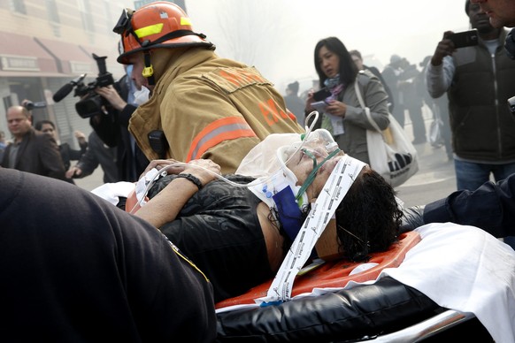 Feuerwehrleute bringen eine verletzte Person in Sicherheit.