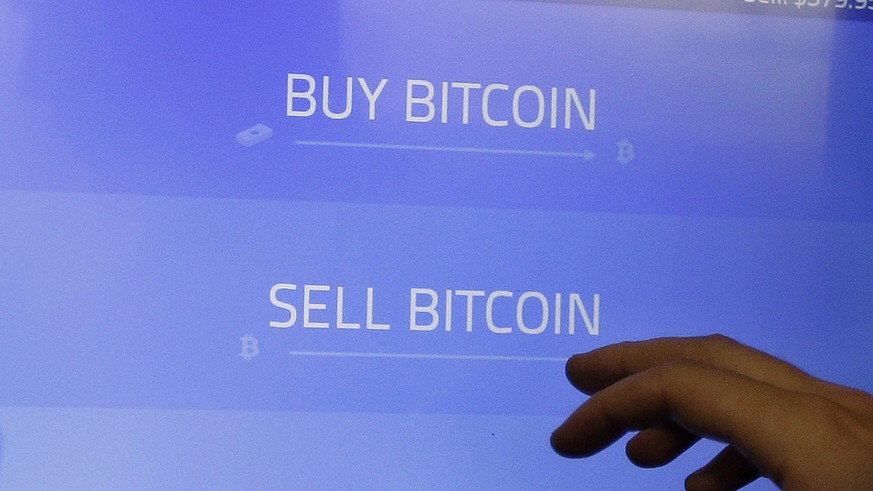 FILE - In this Thursday, March 20, 2014, file photo, Christopher David uses a Robocoin kiosk to sell bitcoins outside of the 500 Startups&#039; Bitcoinference in Mountain View, Calif. Bitcoin, the dig ...