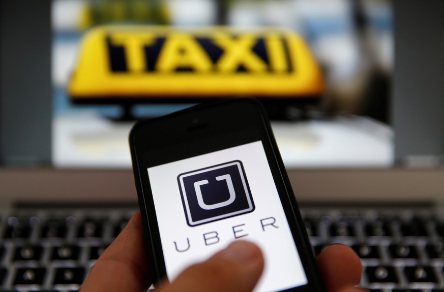 An illustration picture shows the logo of car-sharing service app Uber on a smartphone next to the picture of an official German taxi sign September 15, 2014. REUTERS/Kai Pfaffenbach/Illustration/File ...