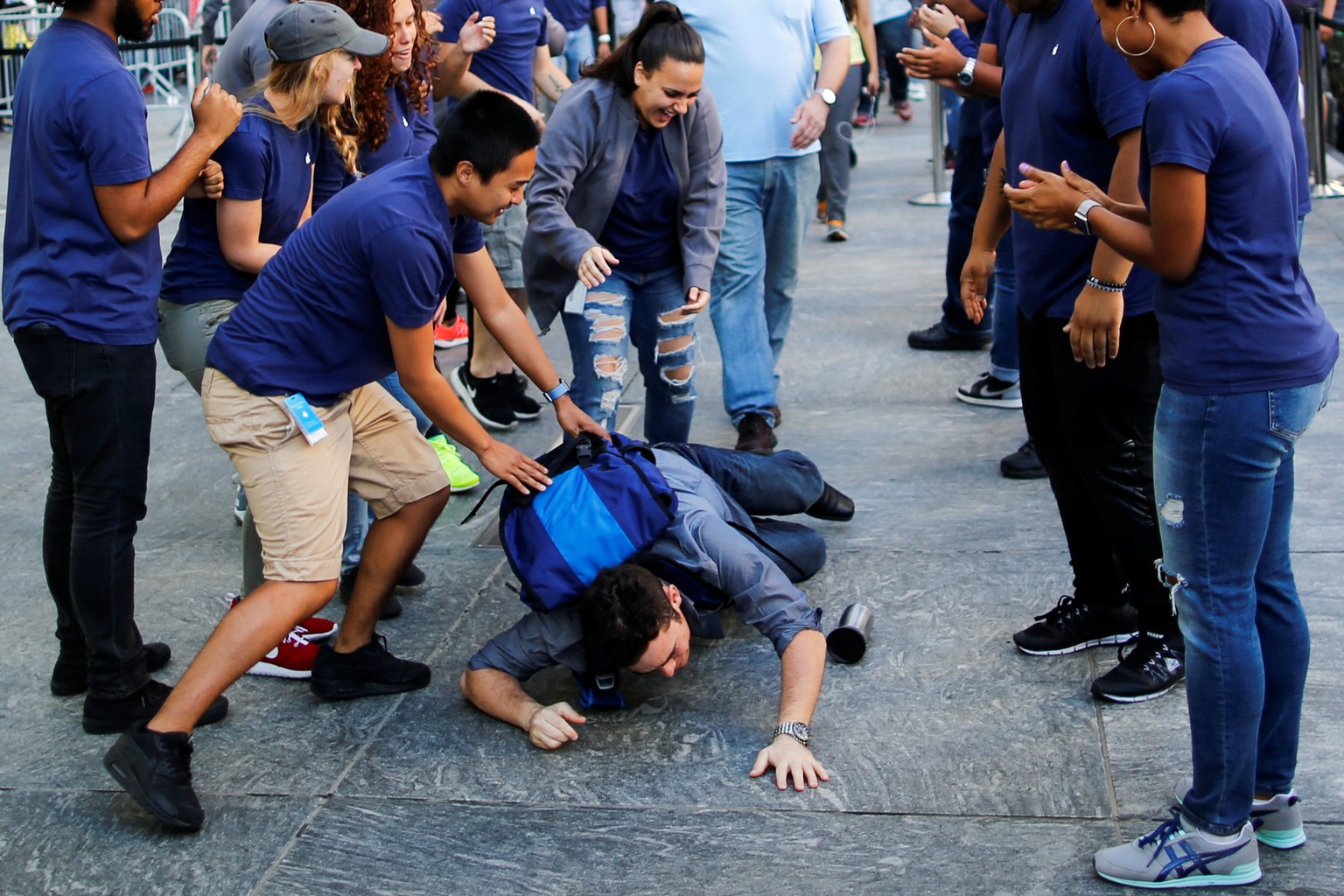 Apple workers assist a customer who fell down before going into the Apple Inc. during the sale of the iPhone 7 smartphone in New York, U.S., September 16, 2016. REUTERS/Eduardo Munoz TPX IMAGES OF THE ...