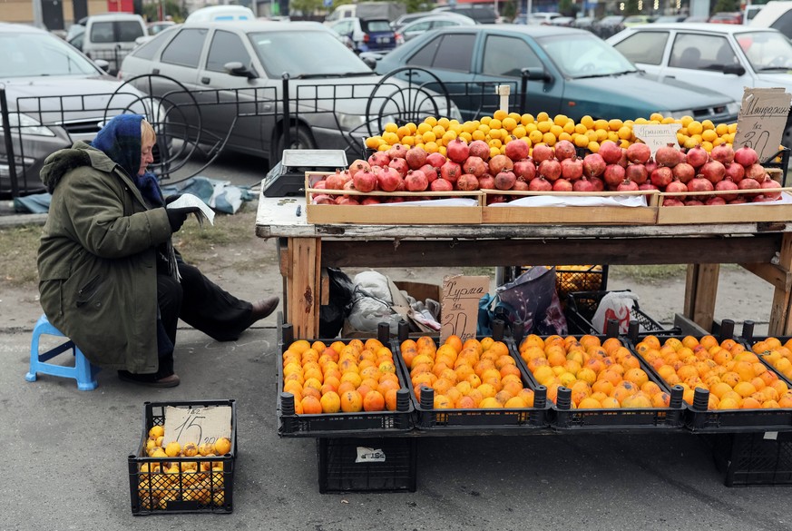 A street vendor reads a newspaper and waits for customers as she sells fruits in Kiev, Ukraine, October 26, 2016. REUTERS/Gleb Garanich