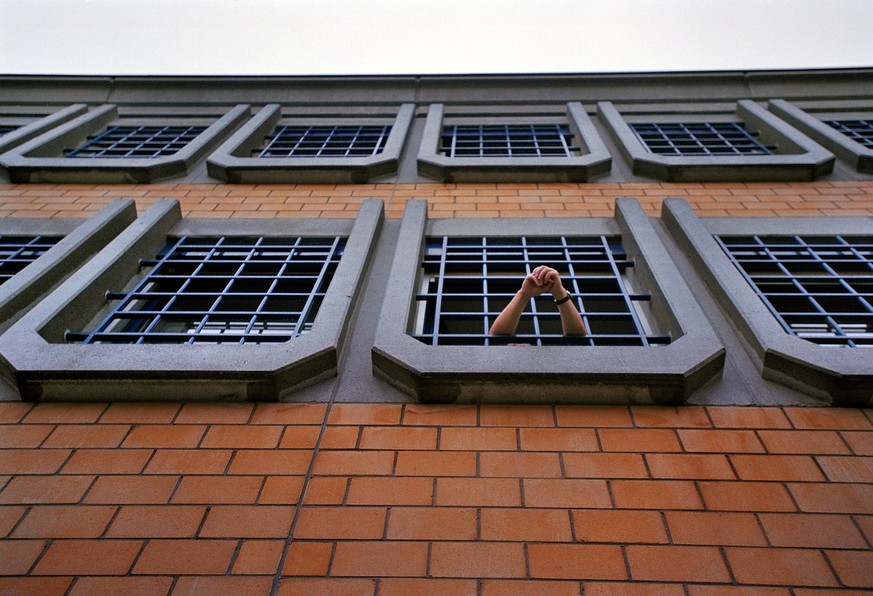 Ein Haeftling der Kantonalen Strafanstalt Poeschwies in Regensdorf (ZH) hat am 15. Dezember 2003 das Fenster seiner Zelle geoeffnet und stuetzt seine Arme auf dem Gitter ab. (KEYSTONE/Gaetan Bally) :  ...