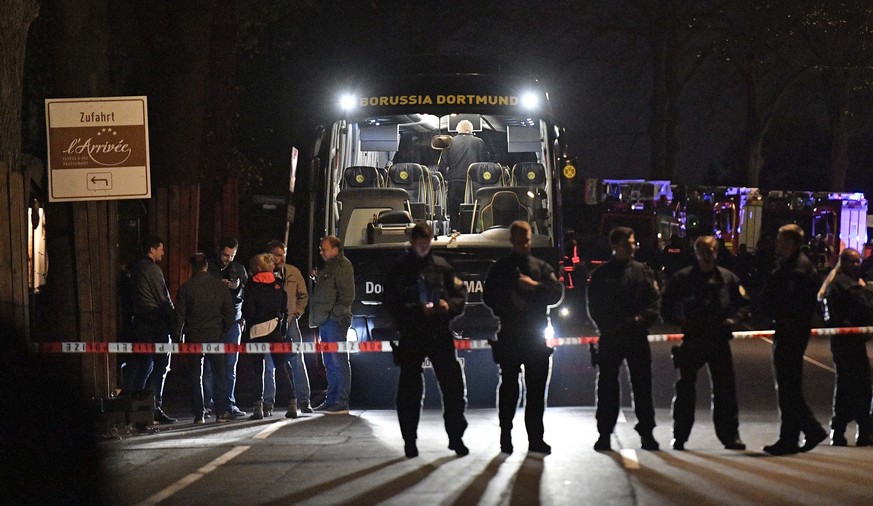FILE - In this April 11, 2017 file photo police officers stand in front of Dortmund&#039;s damaged team bus after explosions which injured two people before the Champions League quarterfinal soccer ma ...