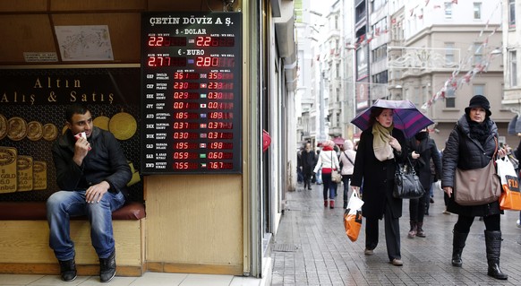 epa04523081 A man sits at a currency exchange office as shoppers walk by on a street in Istanbul, Turkey, 10 December 2014. Turkey&#039;s gross domestic product (GDP) expanded by 1.7 per cent year-on- ...