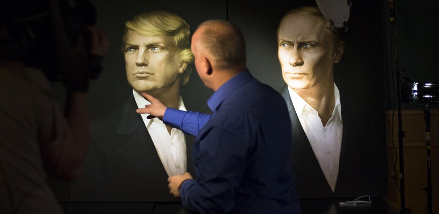 FILE - In this Wednesday, Nov. 9, 2016, file photo, a journalist points at a portrait of U.S. President-elect Donald Trump, with a portrait of Russian President Vladimir Putin during a live telecast o ...