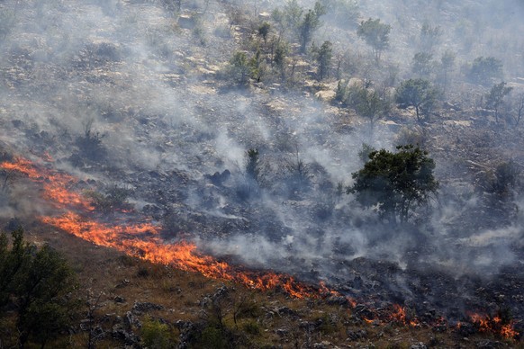 Smoke rises from trees burned by wildfire on a mountain near Montenegro capital Podgorica, Monday, July 17, 2017. At least 100 tourists have been forced to evacuate from a coastal area in Montenegro t ...