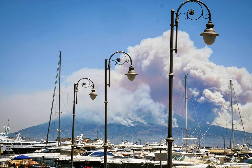 epa06081176 A general view over the city as smoke billows from fires around Mount Vesuvius volcano in Naples, Italy, 11 July 2017. Fires continue to rage after they broke out on 05 July around the act ...