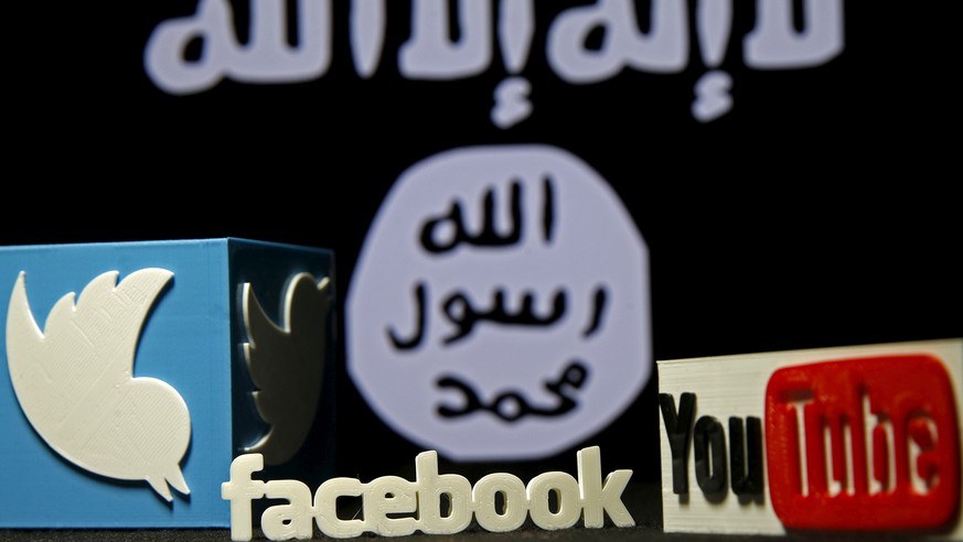 3D plastic representations of the Twitter, Facebook and Youtube logos are seen in front of a displayed ISIS flag in this photo illustration shot February 3, 2016. REUTERS/Dado Ruvic/File Photo