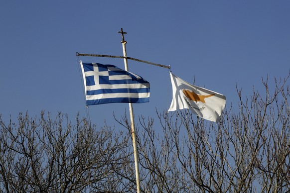 A poll with Greek, left, and Cyprus flags over a Cypriot military guard post by the UN buffer zone, that divides the Greek and Turkish Cypriots controlled areas in the divided capital, Nicosia, Cyprus ...