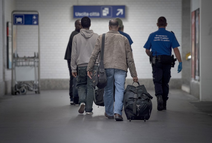 ZUR ASYLSTATISTIK 2015 STELLEN WIR IHNEN AM DONNERSTAG, 28. JANUAR 2016, FOLGENDES ARCHIVBILD ZUR VERFUEGUNG - Ein Angehoeriger des Grenzwachtkorps, rechts, fuehrt angekommene Migranten am Zoll des Ba ...