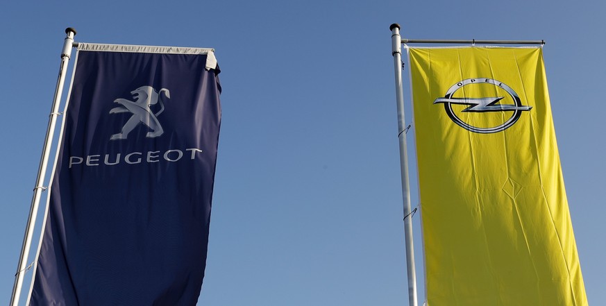 epa05792930 Flags with a logo of Opel and Peugeot fly at a car dealer in Darmstadt, Germany, 14 February 2017. According to media reports on 14 February 2017, French carmaker PSA Group is exploring th ...