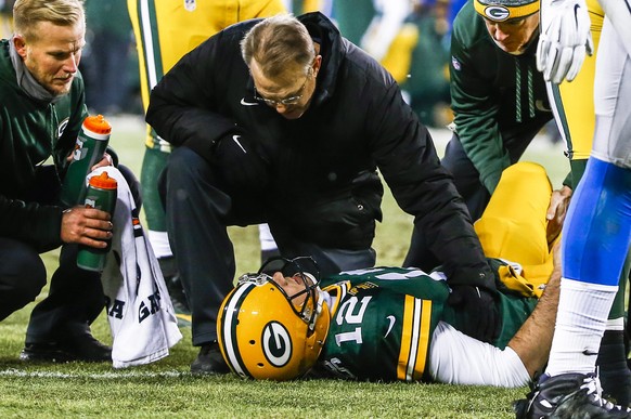 epa04541806 Team trainers tend to Green Bay Packers quarterback Aaron Rodgers as he lies on the ground after sustaining an injury in the first half of their American football game against the Detroit  ...