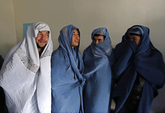 Männer gehen in Kabul in der Burka auf die Strasse.