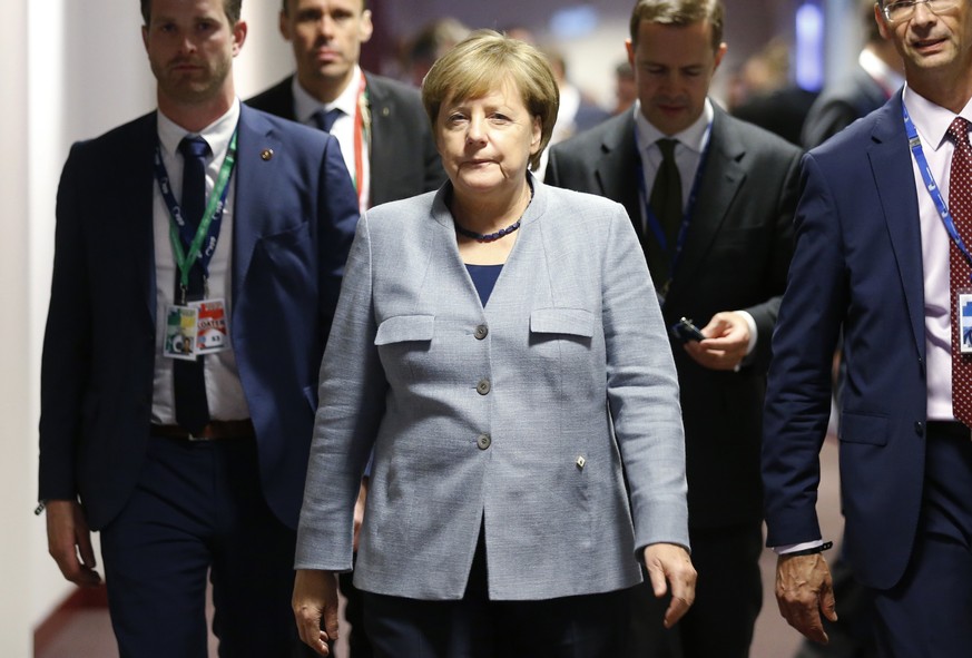 German Chancellor Angela Merkel, center, walks to a meeting on the sidelines of an EU summit in Brussels on Thursday, Oct. 19, 2017. British Prime Minister Theresa May headed to a European Union summi ...