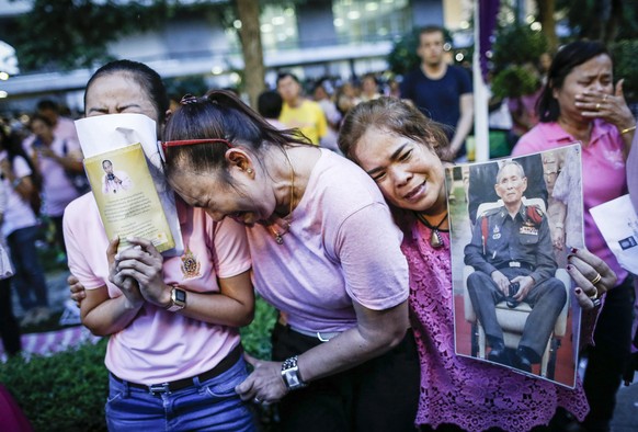 epa05583486 Thai well-wishers weep as they pray for Thai King Bhumibol Adulyadej wishing for his recovery while holding pictures of the King at the Siriraj Hospital in Bangkok, Thailand, 13 October 20 ...