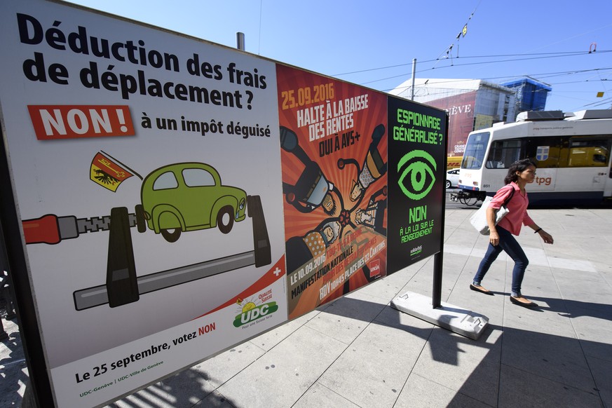 Une personne passe devant des affiches sur les differents themes des votations federales et cantonales, les initiative populaire, pour une economie durable et fondee sur une gestion efficiente des res ...