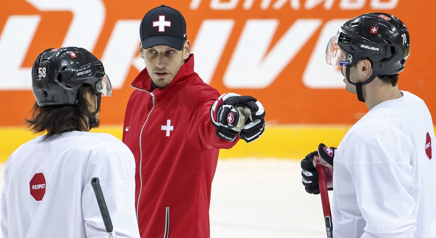 Patrick Fischer, center, head coach of Switzerland national ice hockey team, instructs his players Eric Blum, left, and Denis Hollenstein, right, during a training session of the IIHF 2016 World Champ ...