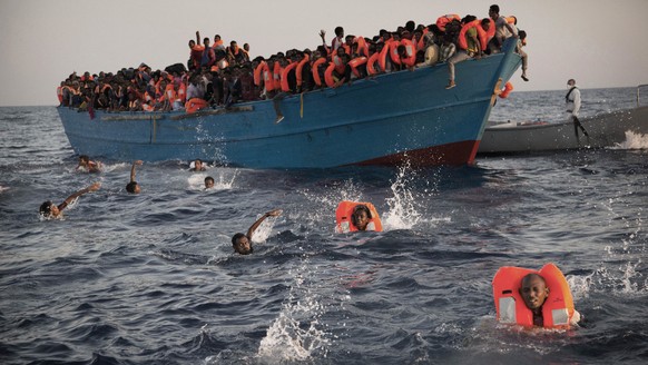 THEMENBILD ZUM SDA TEXTPAKET MIGRATION UND FLUCHT --- 2016 AP YEAR END PHOTOS - Migrants, most from Eritrea, jump into the water from a crowded wooden boat as they are helped by members of an NGO duri ...