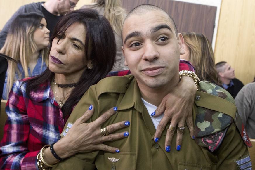 Israeli soldier Elor Azaria is embraced by his mother at the start of his sentencing hearing in Tel Aviv, Israel, Tuesday, Feb. 21, 2017. The court sentenced Azaria to 18 months in prison for the fata ...