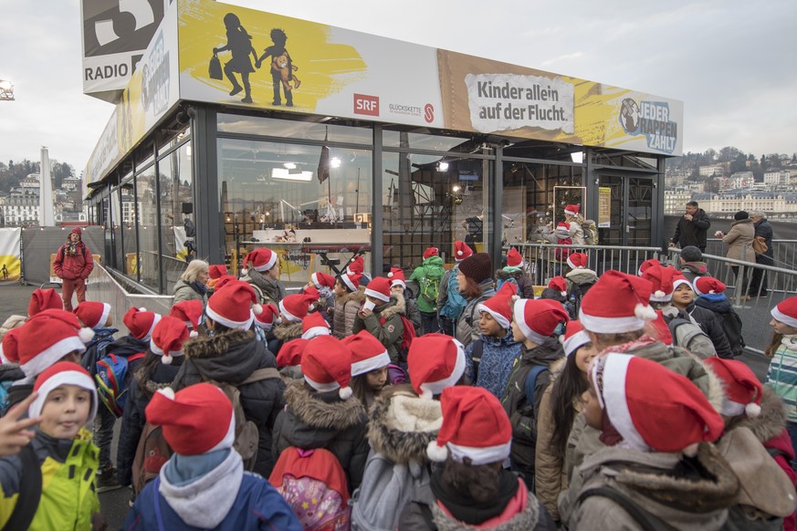 Ein spendende Schulklasse mit roten Muetzen steht rund um die Glasbox, am zweiten Tag der Aktion &quot;Jeder Rappen zaehlt 2016&quot; am Montag, 19. Dezember 2016, auf dem Europaplatz in Luzern. Die S ...