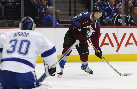 Colorado Avalanche center Mikhail Grigorenko, back, of Russia, looks to shoot the puck at Tampa Bay Lightning goalie Ben Bishop in the first period of an NHL hockey game Sunday, Feb. 19, 2017, in Denv ...