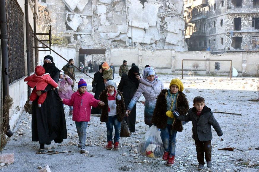 epa05664301 A handout photograph released by the official Syrian Arab News Agency (SANA) shows people carrying their belonging and leaving the eastern neighborhoods of Aleppo, Syria, 07 December 2016. ...