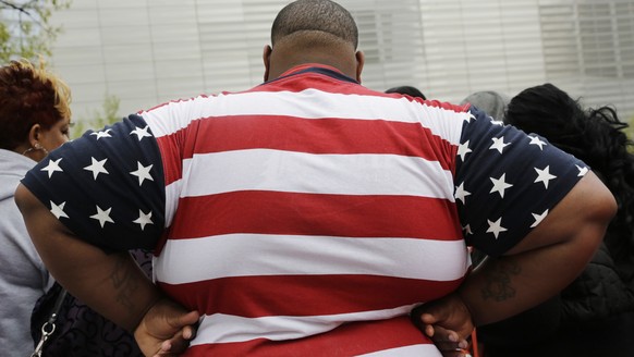 In this Thursday, May 8, 2014 photo, an overweight man wears a shirt patterned after the American flag during a visit to the World Trade Center, in New York. Rising numbers of American adults have the ...