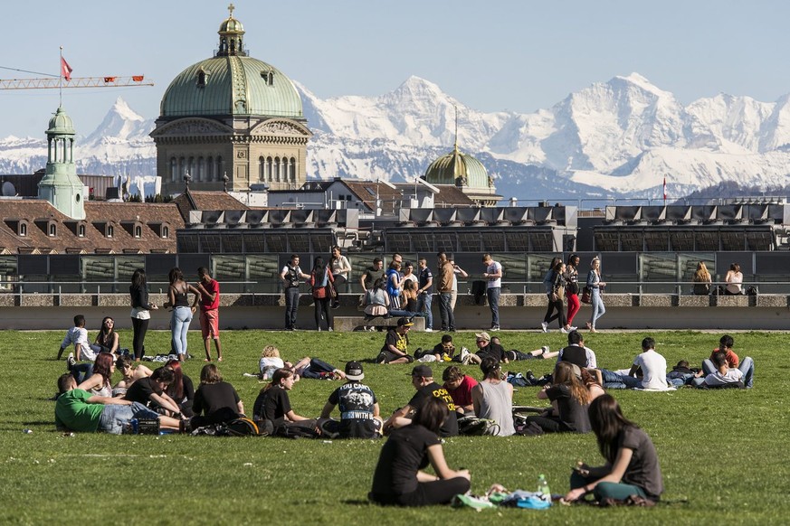 Sonnenhungrige geniessen den langersehnten meteorologischen Fruehlingsbeginn auf der Grossen Schanze in Bern, am Sonntag, 14. April 2013. Im Hintergrund von links, das Finsteraarhorn, das Bundeshaus,  ...